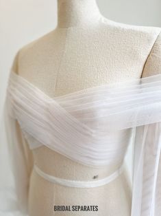 the back of a white wedding dress on a mannequin headdress with sheer tulle