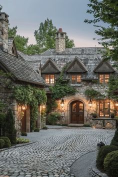 a stone house with lots of greenery and lights on the front door is lit up at night