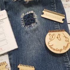 wooden hair combs are sitting on the back of a pair of blue jeans, next to a notepad