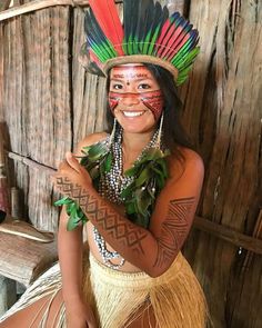 a woman wearing a native american headdress posing for a photo in front of a wooden wall