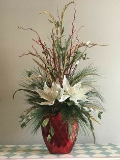 a red vase filled with white flowers on top of a table