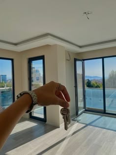 a hand holding a key in front of an open living room with sliding glass doors