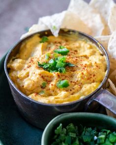 a bowl of hummus and chips on a blue plate with green garnish