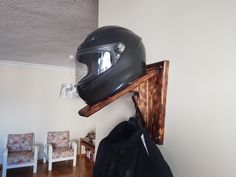 a motorcycle helmet mounted to the side of a wall with a coat rack on it