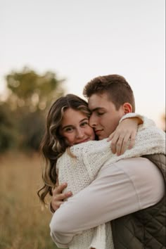 a man and woman hugging each other in a field