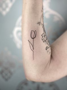 a woman's arm with a flower tattoo on the left side of her arm