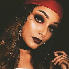 a woman with black makeup and red headband posing for a photo in front of a dark background