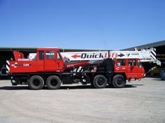 a large red truck parked in front of a hangar