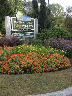 the sign for rolling green nursery is surrounded by colorful flowers and greenery in front of it