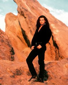 a man standing on top of a rock in front of a large mountain covered in rocks