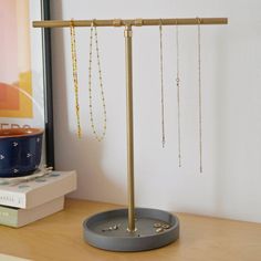 there is a jewelry stand on the table next to some books and a blue bowl