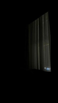 an open window in the dark with white curtains