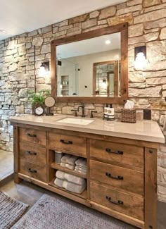 a bathroom with stone walls and wooden cabinets, mirror above the sink, and rug on the floor