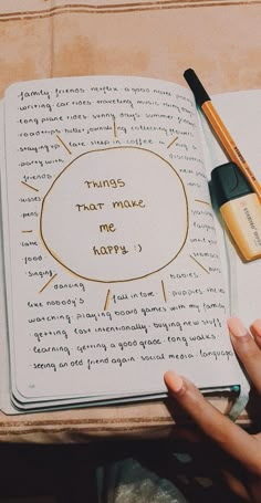 a person holding an open book with writing on it and two pens next to it