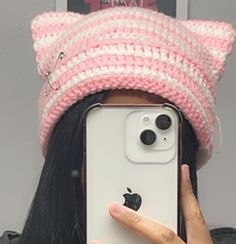 a person taking a selfie with an iphone in front of their face wearing a cat hat