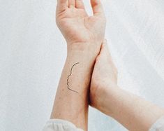 a woman's hand with a small tattoo on her left wrist and the other arm