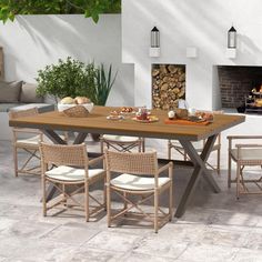 an outdoor dining table with four chairs and a fire place in the background, surrounded by white walls