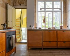 a kitchen with wooden cabinets and an open door leading to the outside area is shown