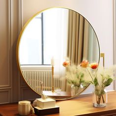 a round mirror sitting on top of a wooden table next to a vase with flowers