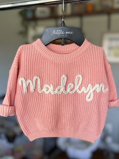 a pink sweater with the word modellyn on it hanging from a clothes line