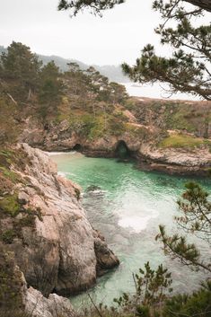 the water is green and blue in this rocky area with trees on either side, looking down at it