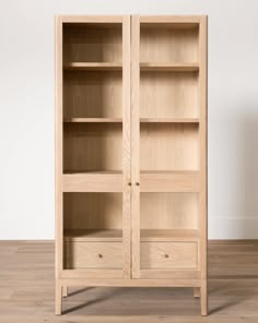 a wooden bookcase sitting on top of a hard wood floor next to a white wall