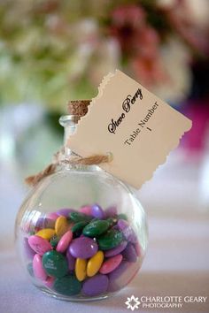 there is a small glass jar with candy in it and a tag on the top