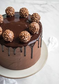 a chocolate cake on a white plate topped with lots of chocolate candies and drizzled in chocolate