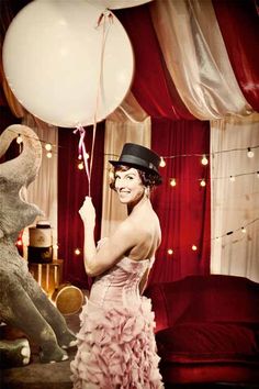 a woman in a dress and hat holding a balloon