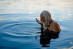 a man with white hair is in the water holding his hand up to his mouth