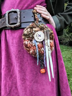 a close up of a person wearing a purple dress and holding a belt with scissors on it