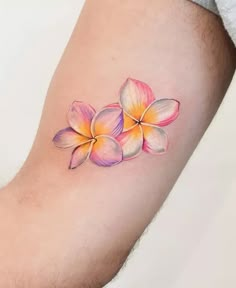 a colorful flower tattoo on the left forearm and arm, with three petals in different colors