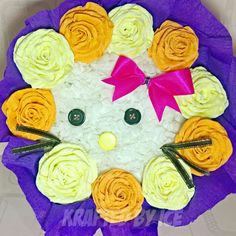 a cake decorated to look like a hello kitty with yellow and pink flowers on it