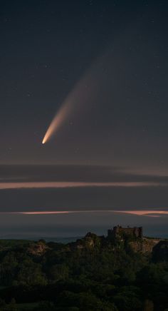 an object is seen in the sky above a hill at night with stars and clouds