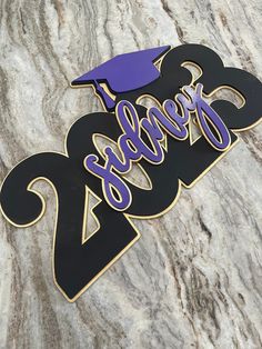 a purple and black graduation sign on a marble surface