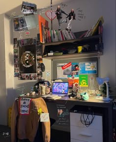 a cluttered desk in an office with lots of stuff on it and pictures hanging from the wall