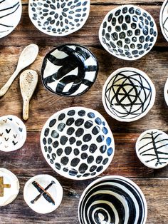 many bowls and spoons are arranged on a wooden table with black and white designs