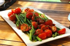 a white plate topped with asparagus and tomatoes