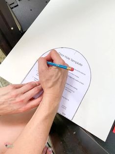 a person writing on a piece of paper with a pencil in their left hand and a sheet of paper behind them