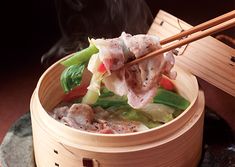 a wooden bowl filled with food and chopsticks