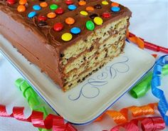 a piece of cake with chocolate frosting and colorful candy on the top is sitting on a plate