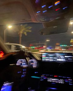 the interior of a car at night with lights on and palm trees in the background