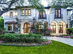 a large white house with lots of windows and bushes around it's front yard