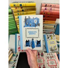 a person holding up a book in front of many books