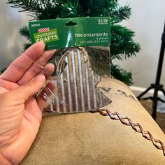 someone holding up a christmas tree ornament in front of a christmas tree on a couch