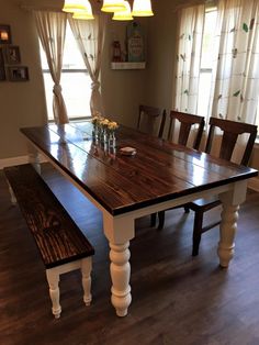 a dining room table with two benches in front of it and three lights hanging from the ceiling