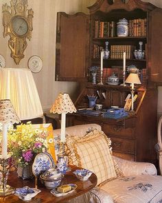 a living room filled with furniture next to a book shelf and lamp on top of a table