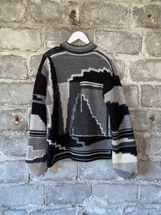 a black and white sweater hanging on a brick wall