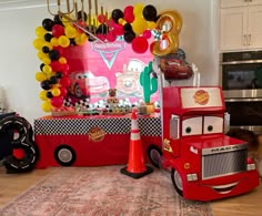 cars birthday party decoration with balloons and decorations on the wall, including a red truck