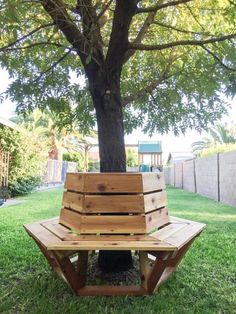 a wooden bench sitting under a tree in the grass